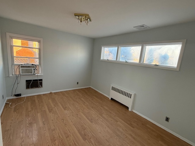 spare room featuring light wood-type flooring, plenty of natural light, radiator, and cooling unit