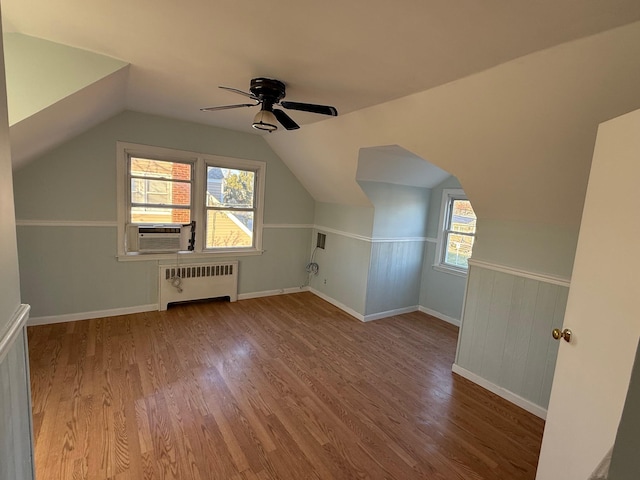 additional living space with radiator, cooling unit, vaulted ceiling, ceiling fan, and wood-type flooring