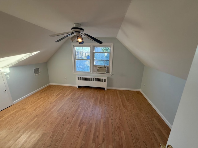 additional living space with radiator, cooling unit, ceiling fan, light hardwood / wood-style floors, and lofted ceiling