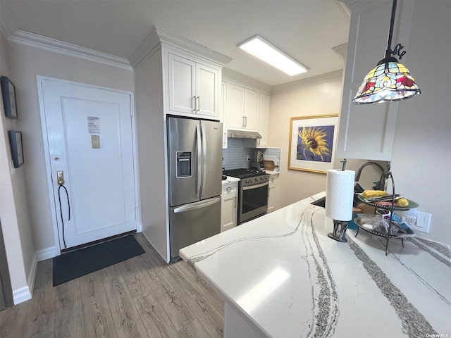 kitchen featuring tasteful backsplash, stainless steel appliances, wood-type flooring, decorative light fixtures, and white cabinets