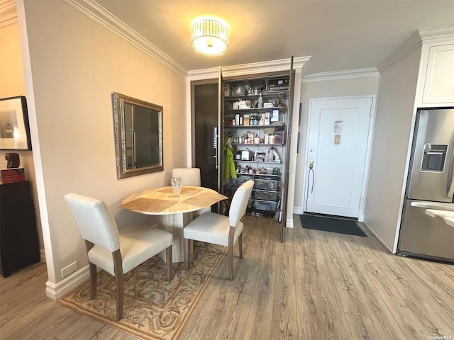 dining space with crown molding and light hardwood / wood-style flooring