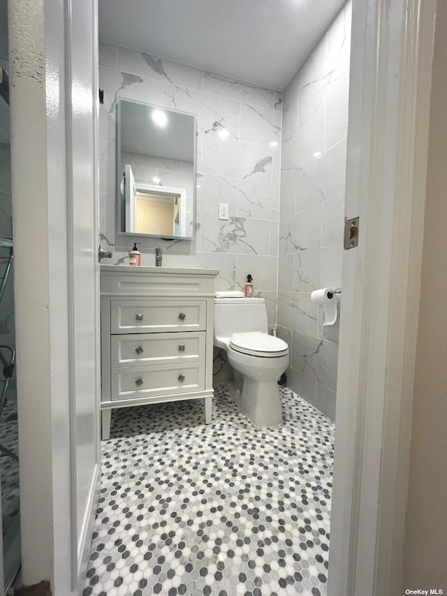 bathroom featuring vanity, toilet, and tile walls