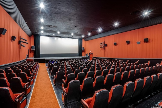 home theater with light colored carpet and wood walls