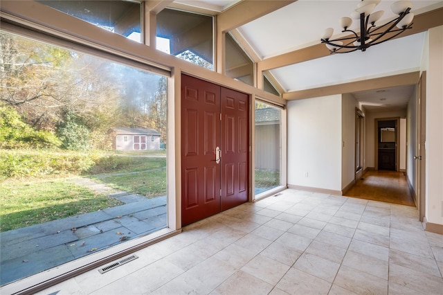 tiled entrance foyer featuring lofted ceiling with beams and an inviting chandelier