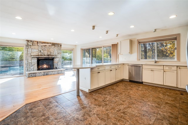 kitchen featuring kitchen peninsula, a wealth of natural light, dishwasher, and a fireplace