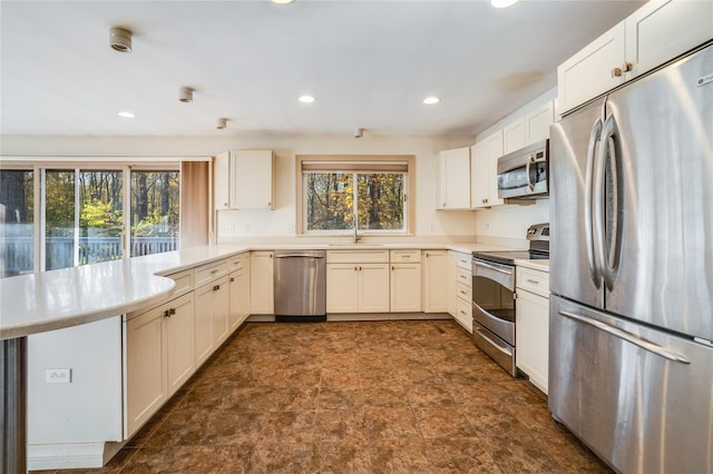 kitchen with white cabinets, sink, kitchen peninsula, and stainless steel appliances