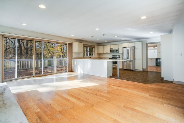 unfurnished living room featuring sink and light hardwood / wood-style flooring