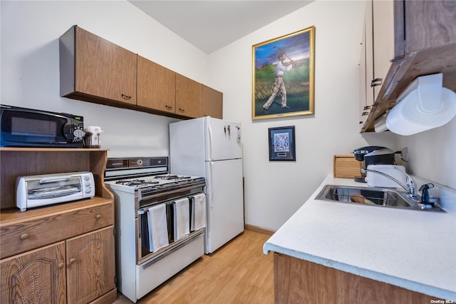 kitchen featuring lofted ceiling, white appliances, sink, and light hardwood / wood-style flooring