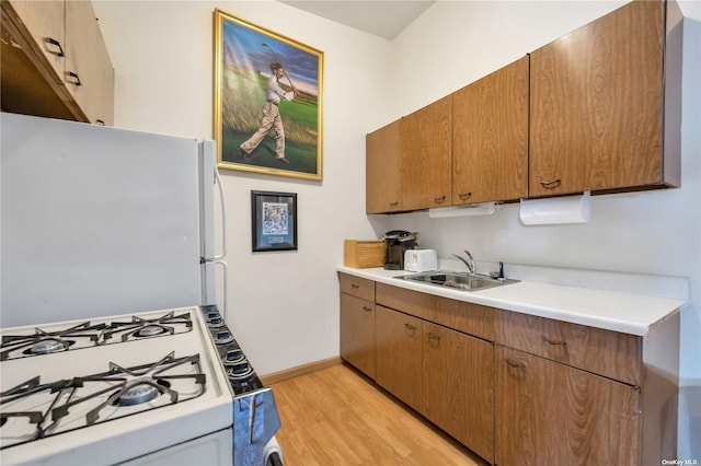 kitchen with light hardwood / wood-style floors, white appliances, and sink