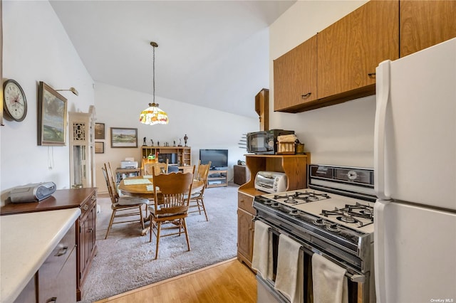 kitchen featuring hanging light fixtures, light hardwood / wood-style flooring, range with gas cooktop, white refrigerator, and vaulted ceiling