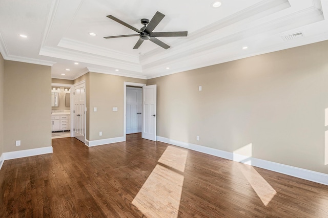 interior space with ensuite bath, ceiling fan, dark wood-type flooring, crown molding, and a tray ceiling