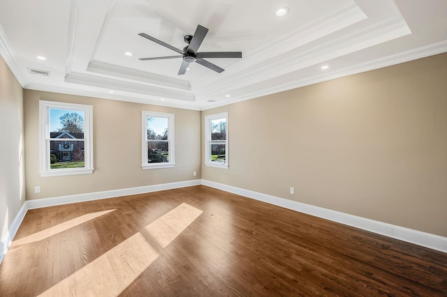 empty room with a tray ceiling, crown molding, ceiling fan, and hardwood / wood-style flooring