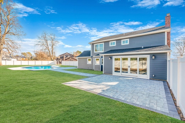 rear view of property with a lawn, a patio area, and a fenced in pool