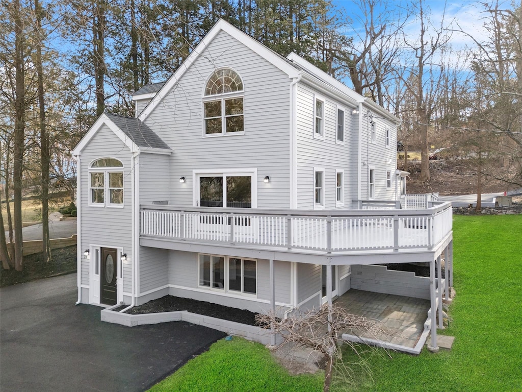 rear view of property featuring a yard, a patio, and a deck