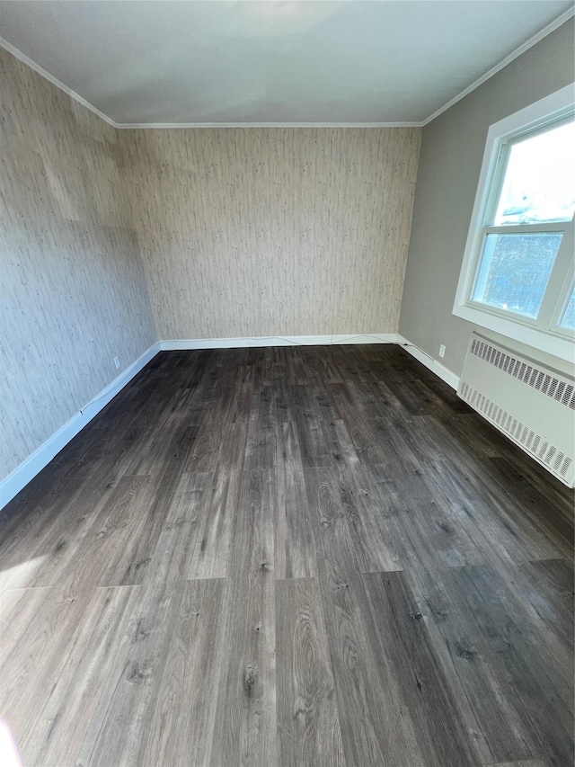 spare room featuring radiator, crown molding, and dark hardwood / wood-style flooring