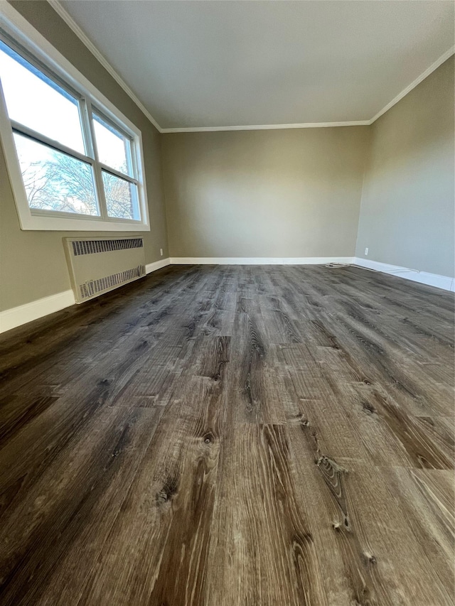 spare room with ornamental molding, dark wood-type flooring, and radiator