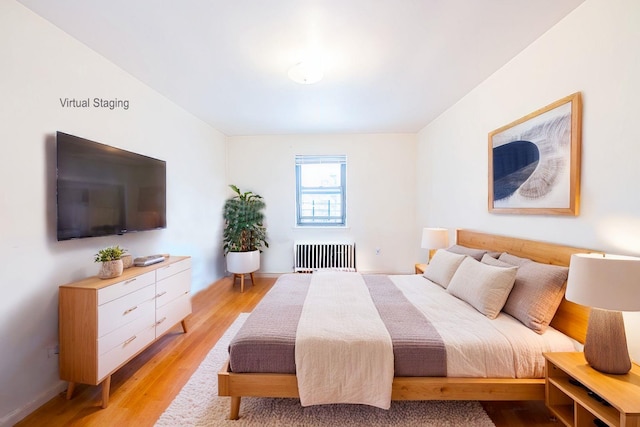 bedroom with radiator heating unit and light wood-type flooring