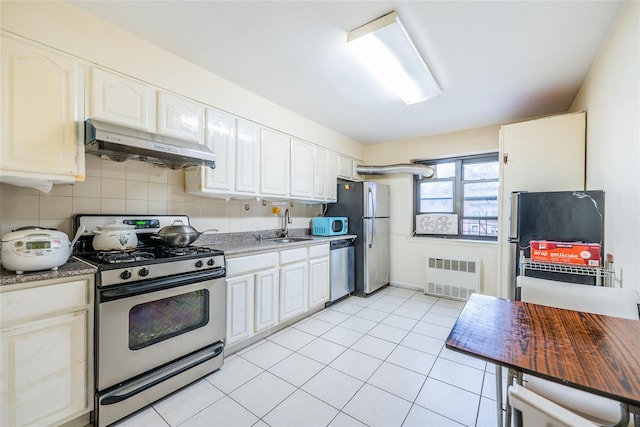 kitchen with radiator, light tile patterned floors, sink, appliances with stainless steel finishes, and white cabinetry