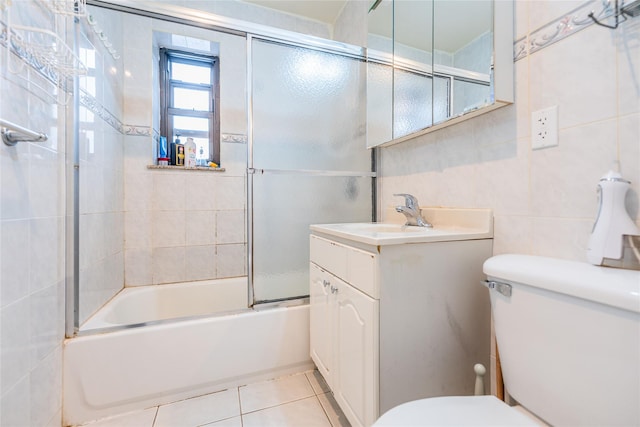 full bathroom featuring bath / shower combo with glass door, tile walls, tile patterned flooring, vanity, and toilet