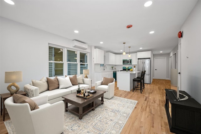 living room featuring a wall mounted air conditioner, light wood-type flooring, and sink