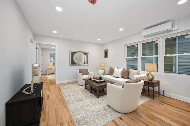 living room with a wall mounted air conditioner and light hardwood / wood-style flooring