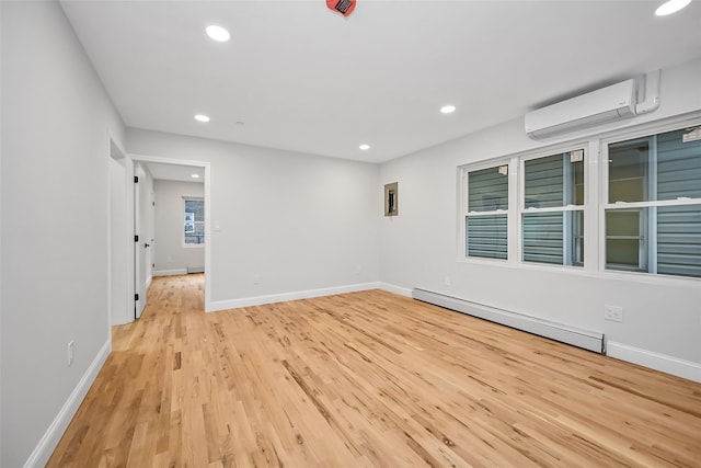 empty room with a wall mounted AC, light wood-type flooring, and a baseboard heating unit