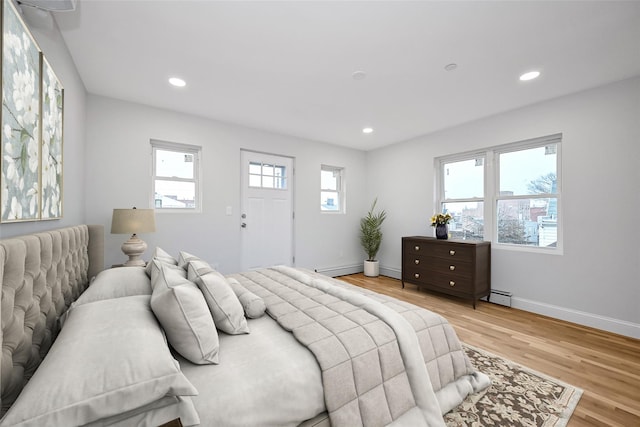 bedroom with baseboard heating and light hardwood / wood-style flooring