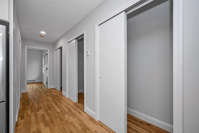 corridor with a baseboard radiator and light hardwood / wood-style flooring