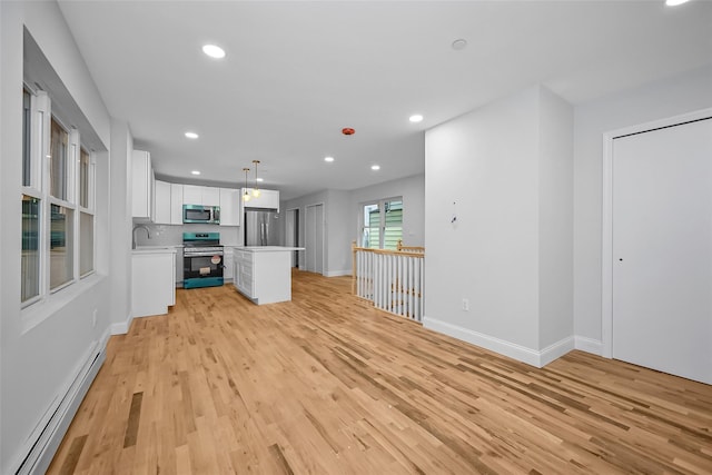 kitchen featuring light wood-type flooring, stainless steel appliances, baseboard heating, decorative light fixtures, and white cabinets