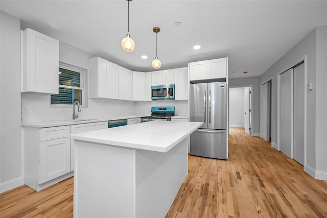 kitchen with white cabinets, stainless steel appliances, a kitchen island, and sink