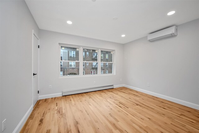 spare room featuring light wood-type flooring, baseboard heating, and a wall mounted AC