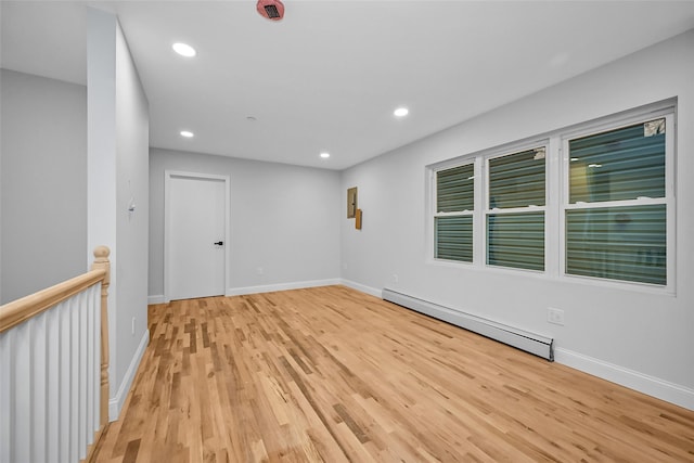 empty room featuring baseboard heating and light hardwood / wood-style floors