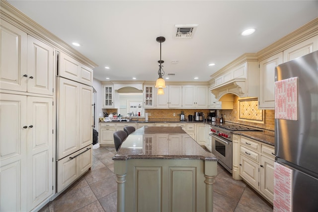 kitchen with decorative backsplash, dark stone counters, stainless steel appliances, pendant lighting, and a center island