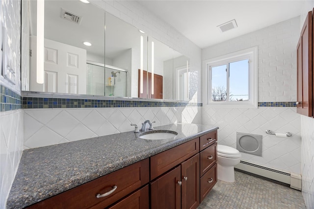 bathroom featuring a baseboard heating unit, toilet, a shower with door, vanity, and tile walls