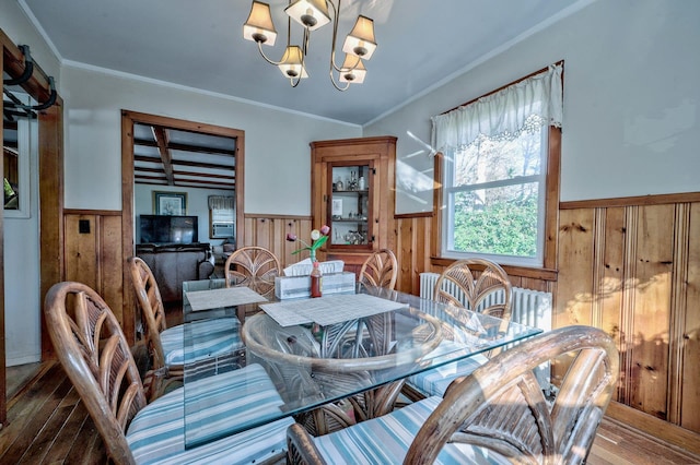 dining room featuring wood walls, an inviting chandelier, ornamental molding, and hardwood / wood-style flooring