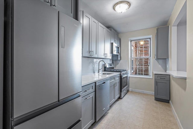 kitchen featuring gray cabinets, sink, light tile patterned floors, and stainless steel appliances