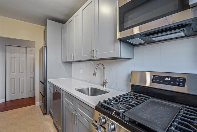 kitchen featuring light stone countertops, appliances with stainless steel finishes, tasteful backsplash, sink, and light tile patterned floors