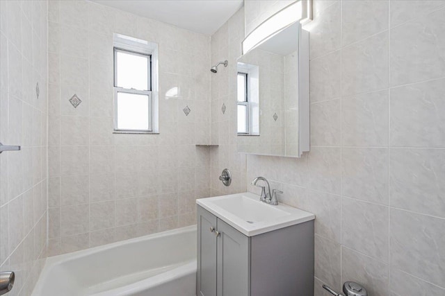 bathroom featuring vanity, tiled shower / bath combo, and tile walls