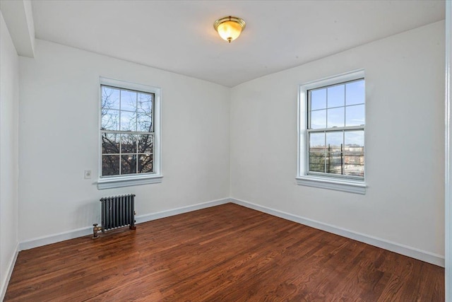 empty room featuring dark hardwood / wood-style floors, a healthy amount of sunlight, and radiator