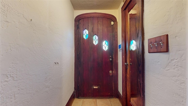 doorway with light tile patterned floors and a textured ceiling