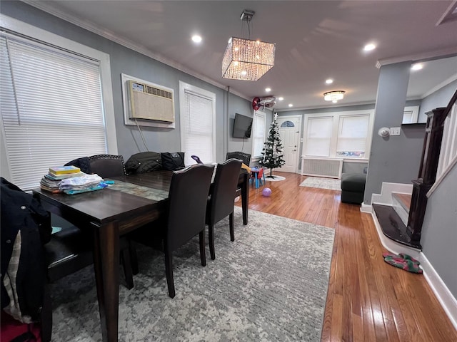 dining room with radiator heating unit, an inviting chandelier, light hardwood / wood-style flooring, a wall unit AC, and crown molding