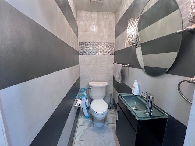 bathroom with vanity, tile walls, and toilet