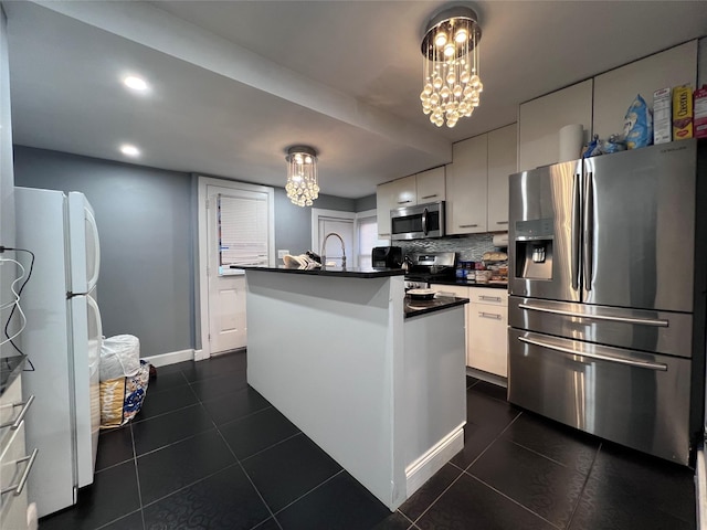 kitchen with white cabinets, hanging light fixtures, an island with sink, a notable chandelier, and stainless steel appliances