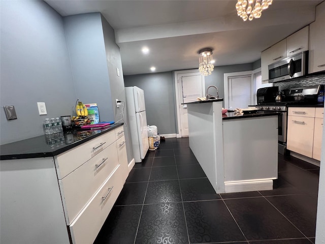 kitchen featuring appliances with stainless steel finishes, decorative light fixtures, and white cabinetry