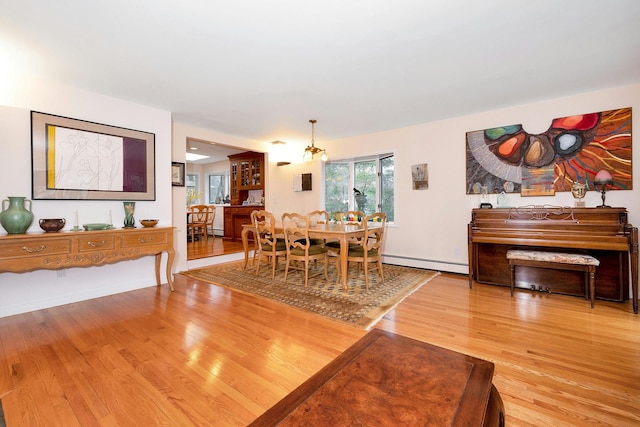 dining space with a notable chandelier, hardwood / wood-style floors, and a baseboard heating unit