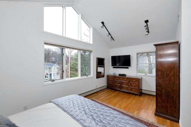 bedroom with multiple windows, light hardwood / wood-style floors, and baseboard heating