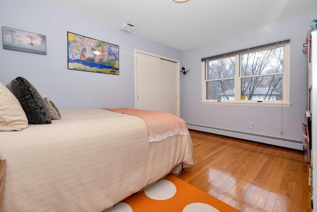 bedroom featuring a baseboard radiator, hardwood / wood-style floors, and a closet