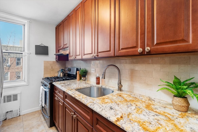 kitchen featuring gas stove, radiator, sink, light stone counters, and backsplash