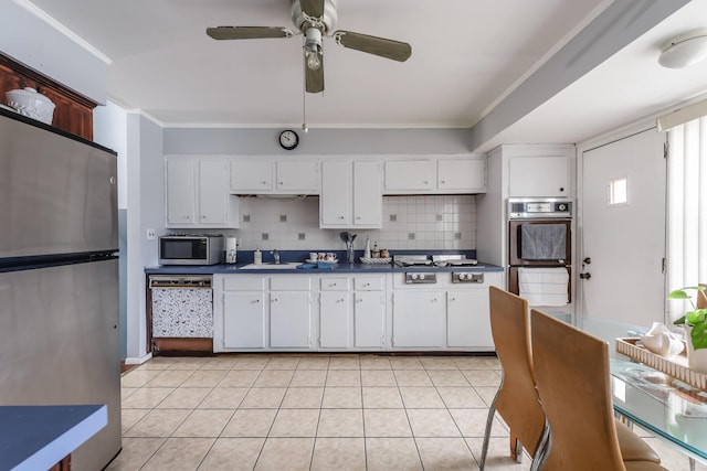 kitchen with sink, decorative backsplash, ornamental molding, appliances with stainless steel finishes, and white cabinetry