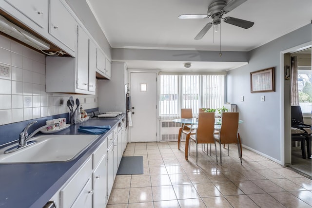 kitchen featuring radiator, white cabinetry, sink, decorative backsplash, and light tile patterned flooring